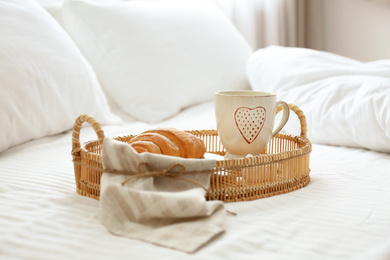 Photo of Delicious morning coffee and croissant on bed