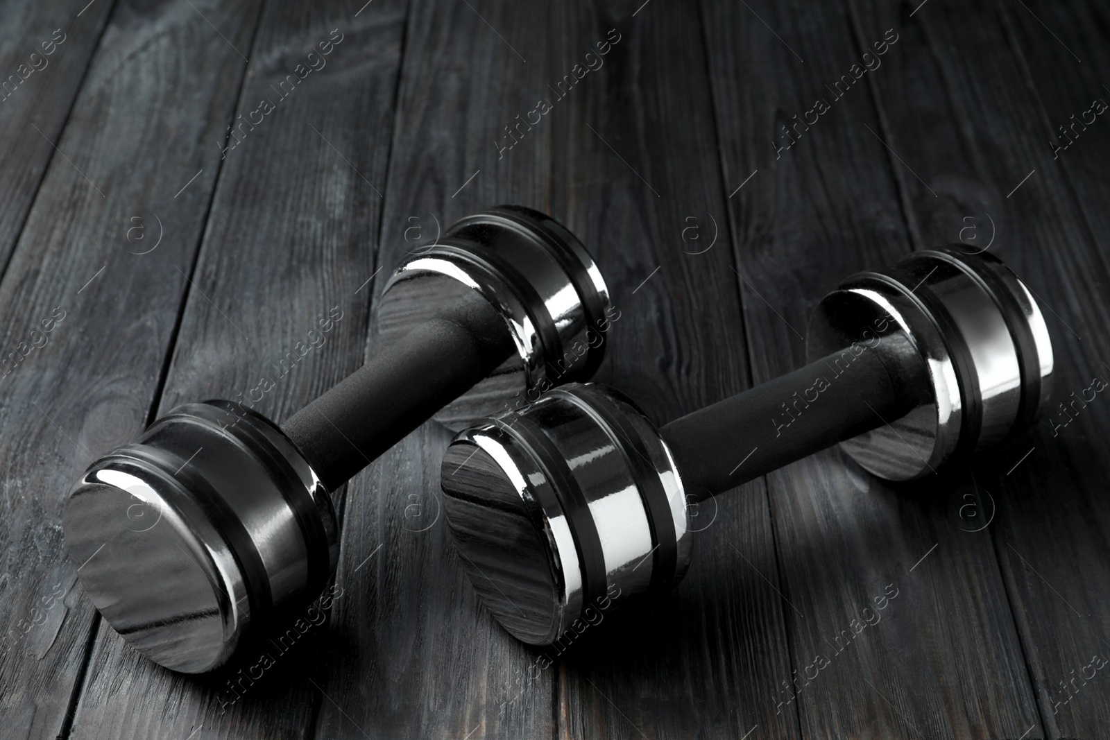 Photo of Two metal dumbbells on black wooden table