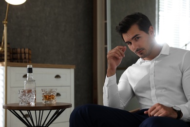 Man near table with whiskey at home