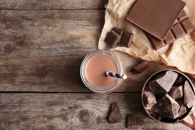 Photo of Flat lay composition with jar of tasty chocolate milk and space for text on wooden background. Dairy drink