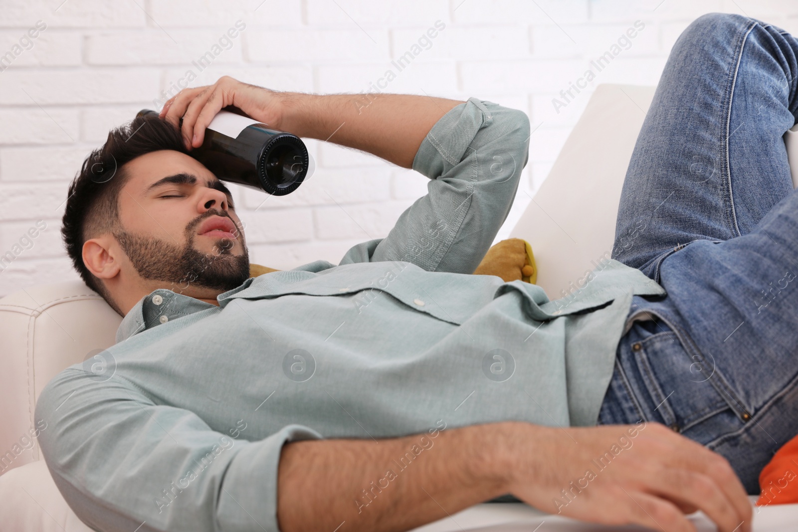 Photo of Young man suffering from hangover in room after party