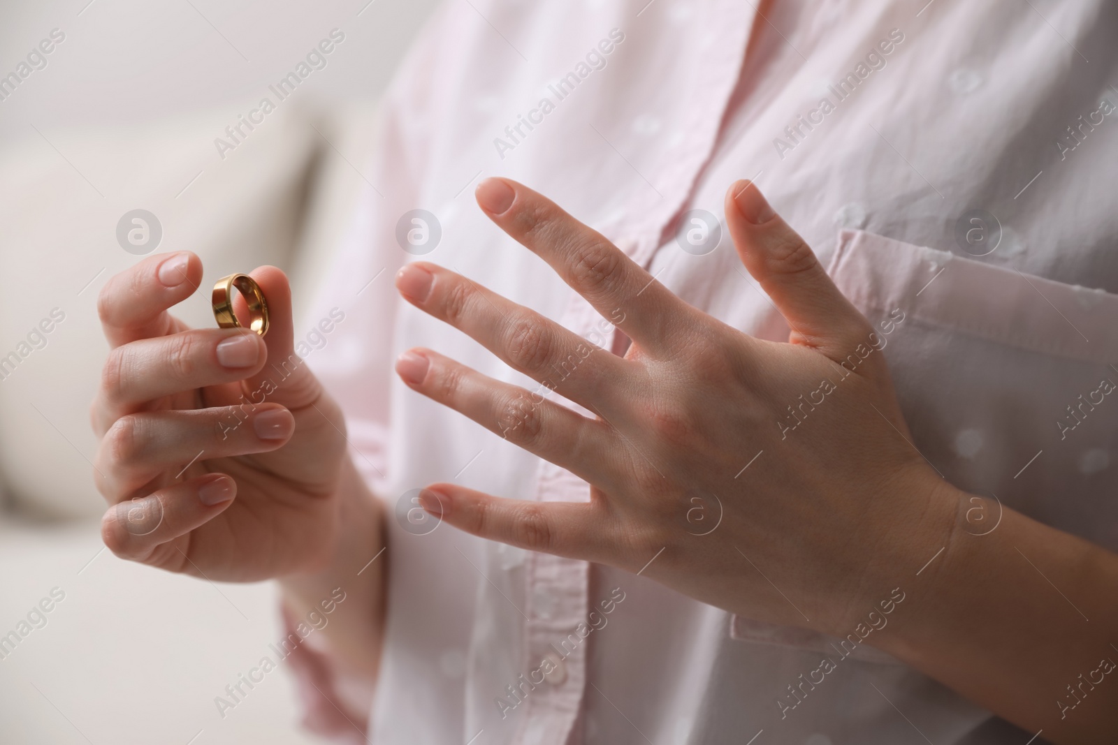 Photo of Woman taking off wedding ring indoors, closeup. Divorce concept