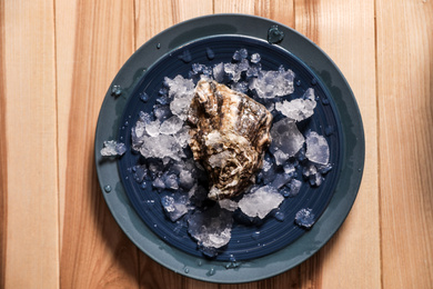 Fresh oyster with ice on wooden table, top view