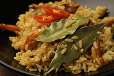 Delicious pilaf and bay leaves in bowl, closeup