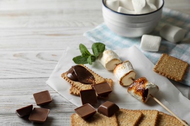 Photo of Ingredients for delicious sandwich with roasted marshmallows and chocolate on white wooden table, closeup
