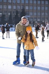 Father and daughter spending time together at outdoor ice skating rink