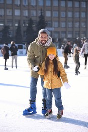 Image of Father and daughter spending time together at outdoor ice skating rink