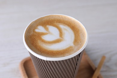 Coffee to go. Paper cup with tasty drink on white table, closeup