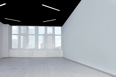 Photo of Empty office room with black ceiling and clean windows. Interior design
