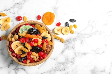 Bowl of different dried fruits on marble background, top view with space for text. Healthy lifestyle
