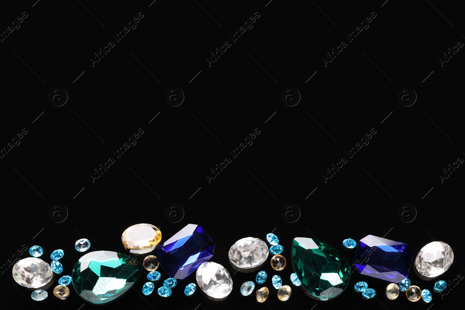 Photo of Different beautiful gemstones for jewelry on black background, flat lay. Space for text