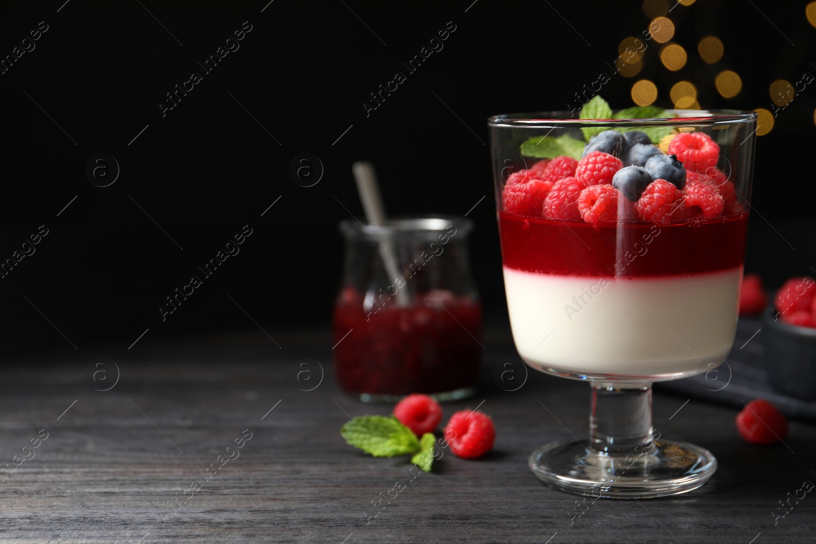 Photo of Delicious panna cotta with berries on black wooden table. Space for text