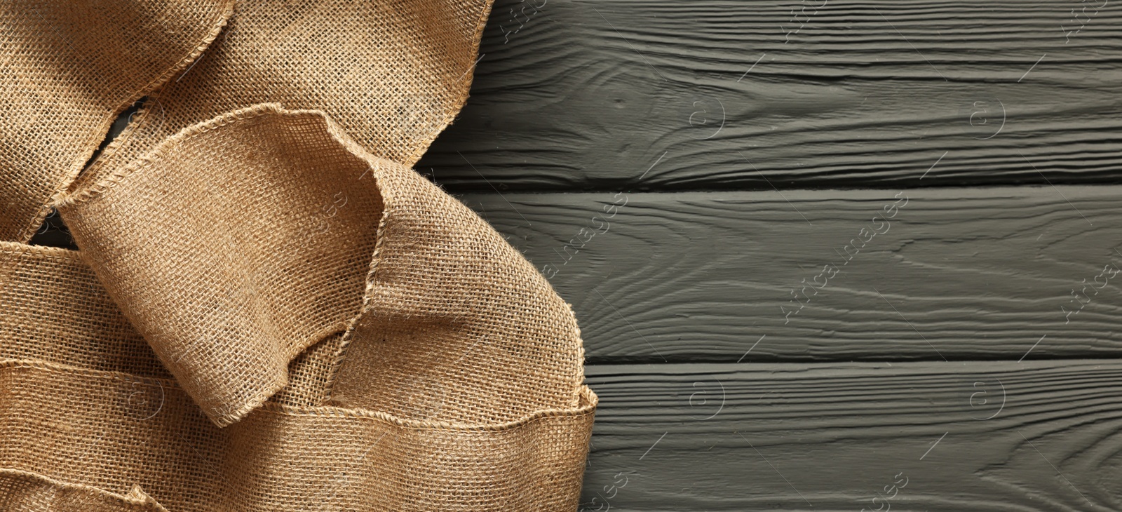 Photo of Pieces of burlap fabric on grey wooden table, top view. Space for text