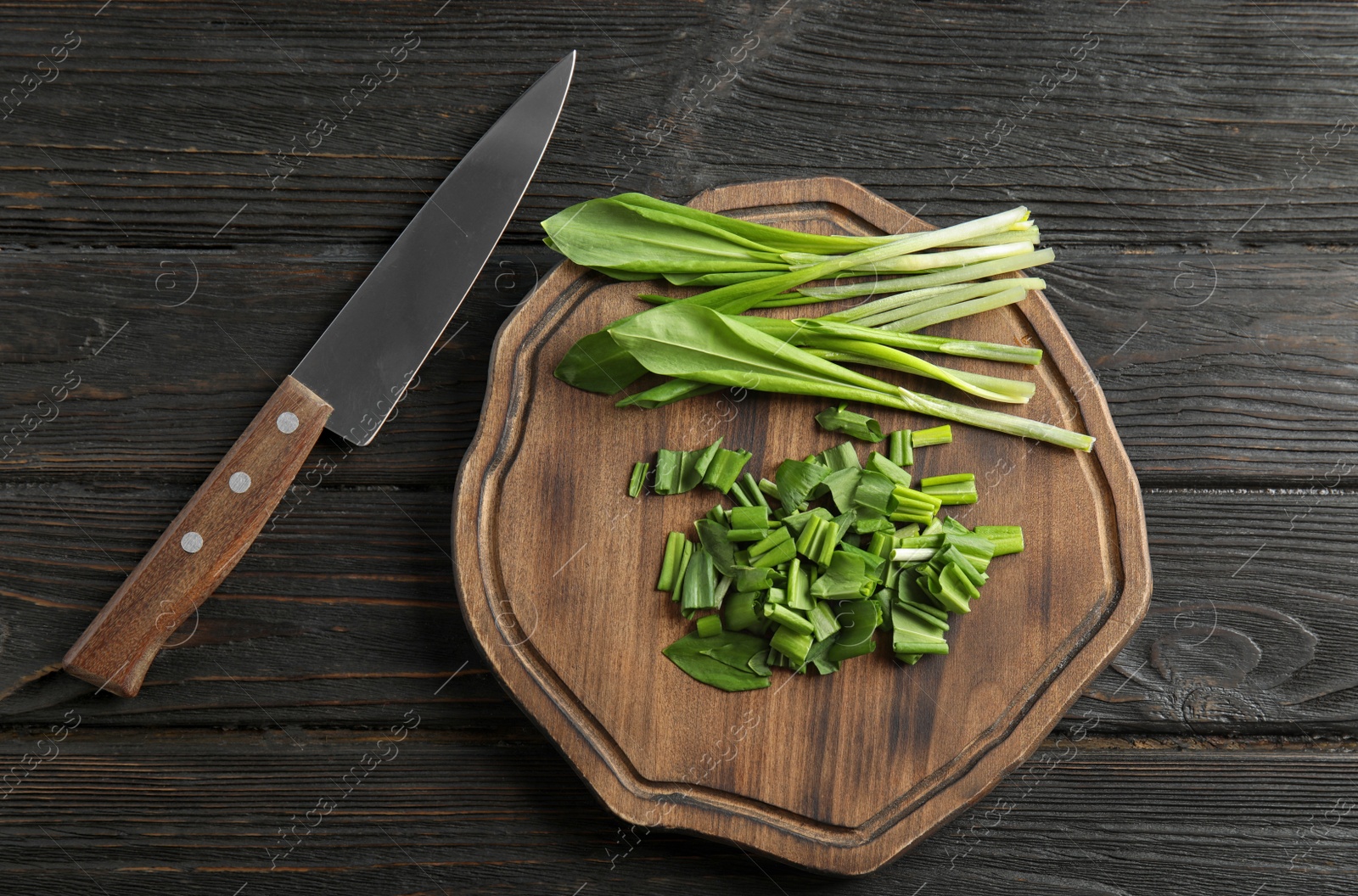 Photo of Board with wild garlic or ramson and knife on wooden table, flat lay