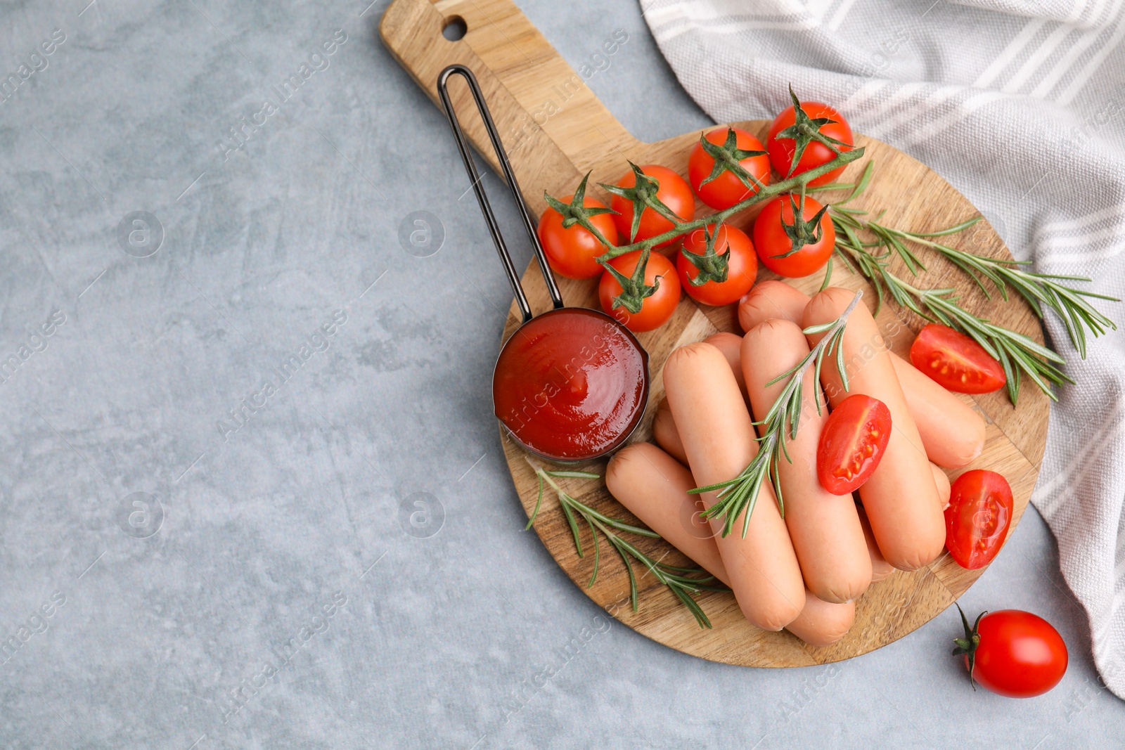 Photo of Delicious boiled sausages, tomato sauce, tomatoes and rosemary on gray table, top view. Space for text