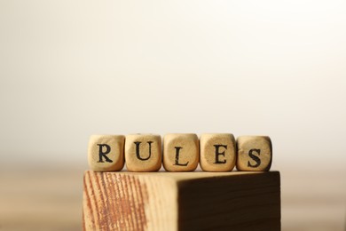 Photo of Word Rules made of cubes with letters on wooden block, space for text