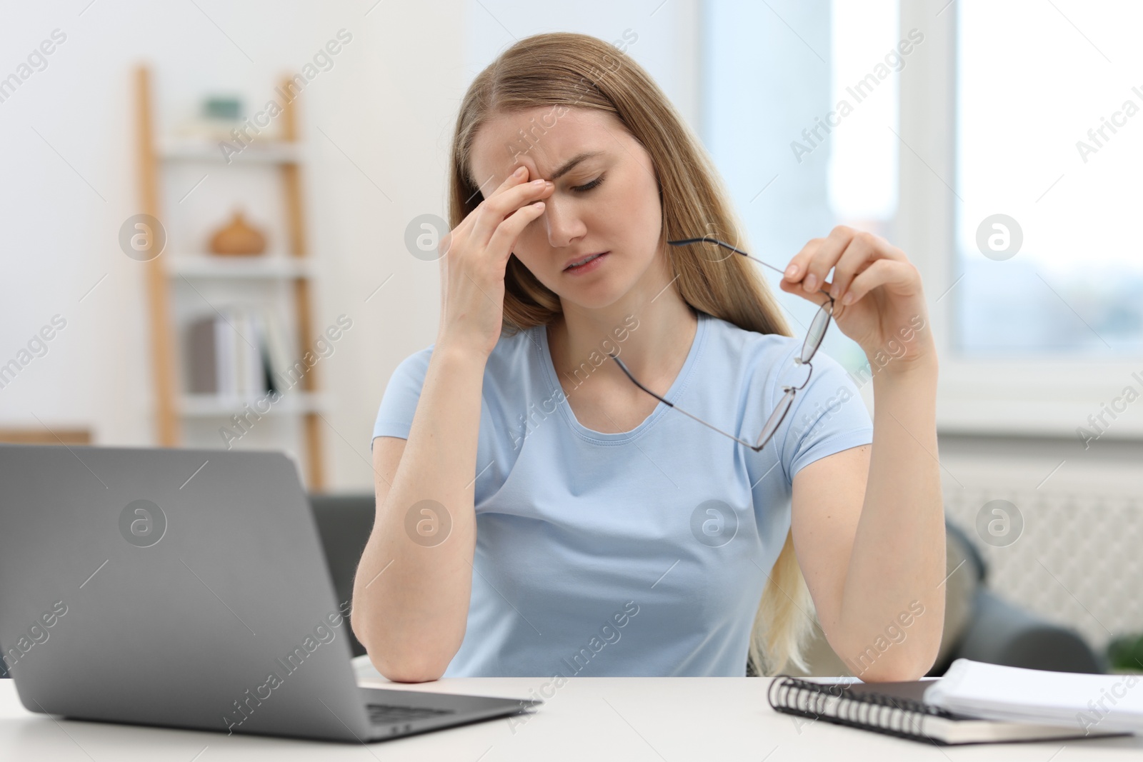 Photo of Overwhelmed young woman sitting with laptop at table in room