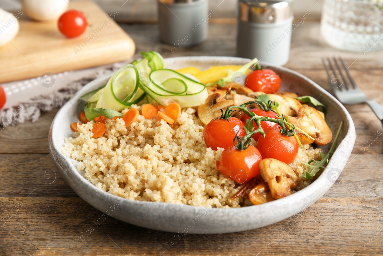 Photo of Plate with healthy quinoa salad and vegetables on wooden table