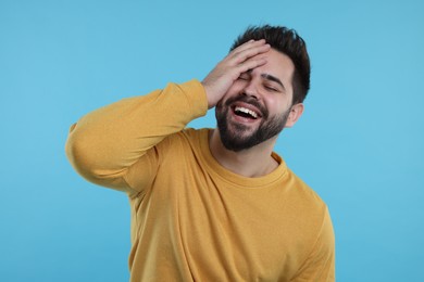 Handsome young man laughing on light blue background