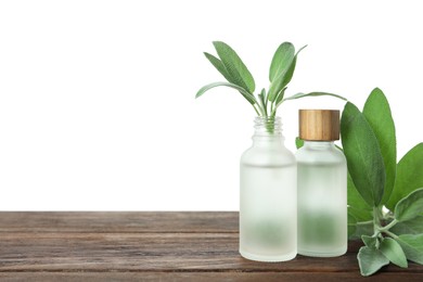 Photo of Bottles of essential oil and sage on wooden table against white background