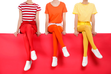 Photo of Women wearing bright tights sitting together on color background, closeup