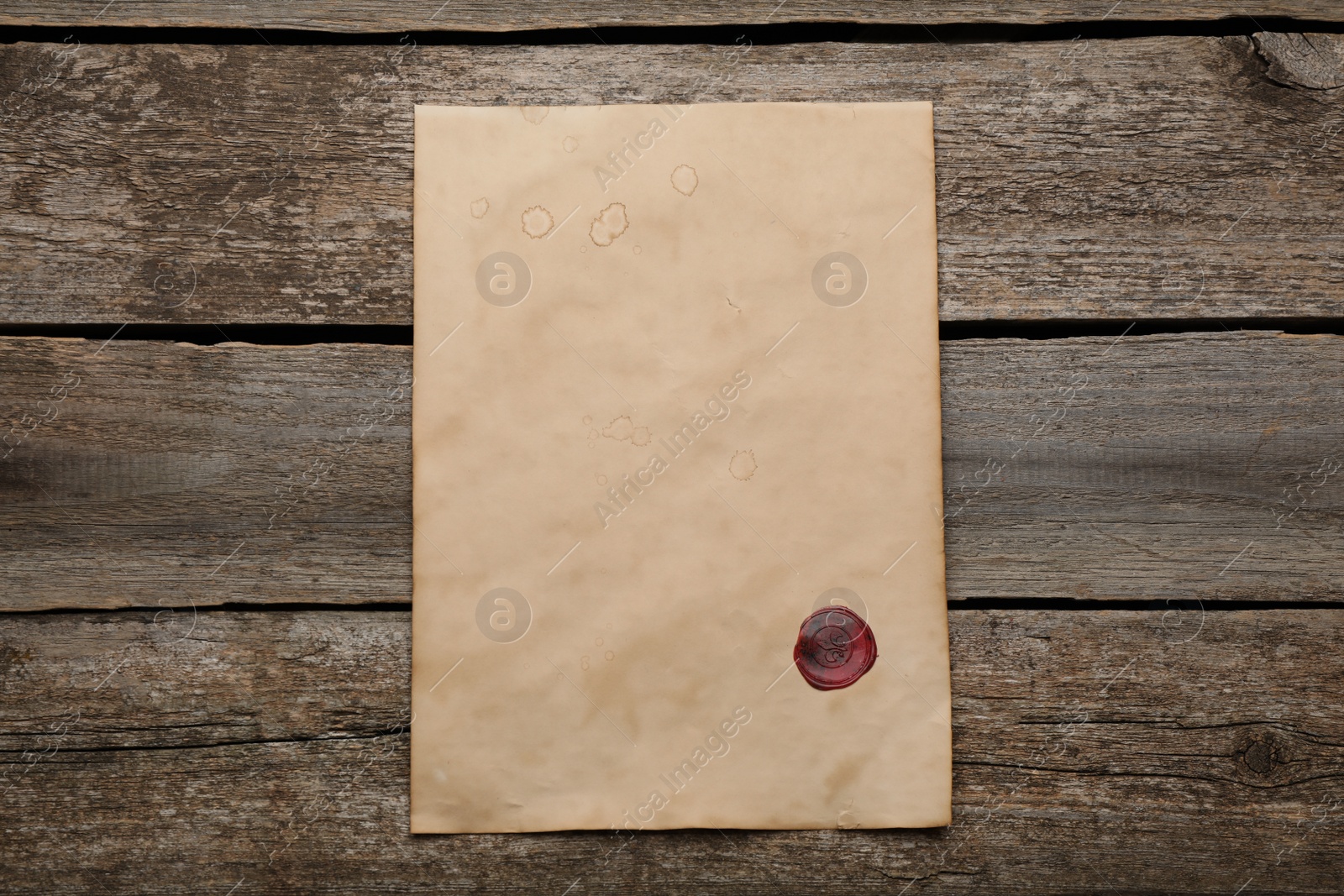 Photo of Sheet of old parchment paper with wax stamp on wooden table, top view. Space for design