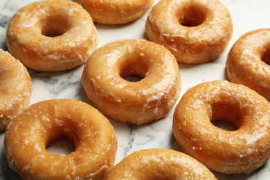 Delicious glazed donuts on marble table, closeup