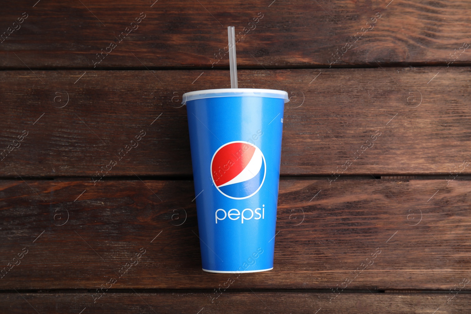 Photo of MYKOLAIV, UKRAINE - JUNE 08, 2021: Paper Pepsi cup on wooden background, top view
