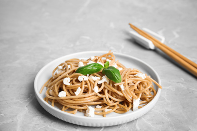 Photo of Tasty buckwheat noodles with chopsticks on light grey table