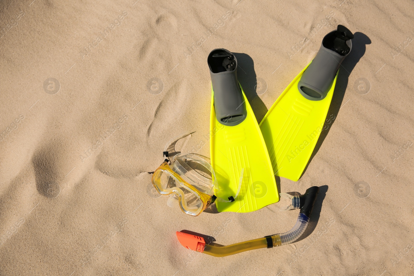 Photo of Pair of flippers, snorkel and diving mask on sandy beach, flat lay. Space for text