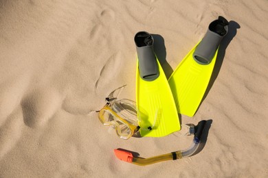 Photo of Pair of flippers, snorkel and diving mask on sandy beach, flat lay. Space for text