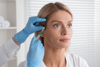 Photo of Trichologist giving injection to patient in clinic, closeup