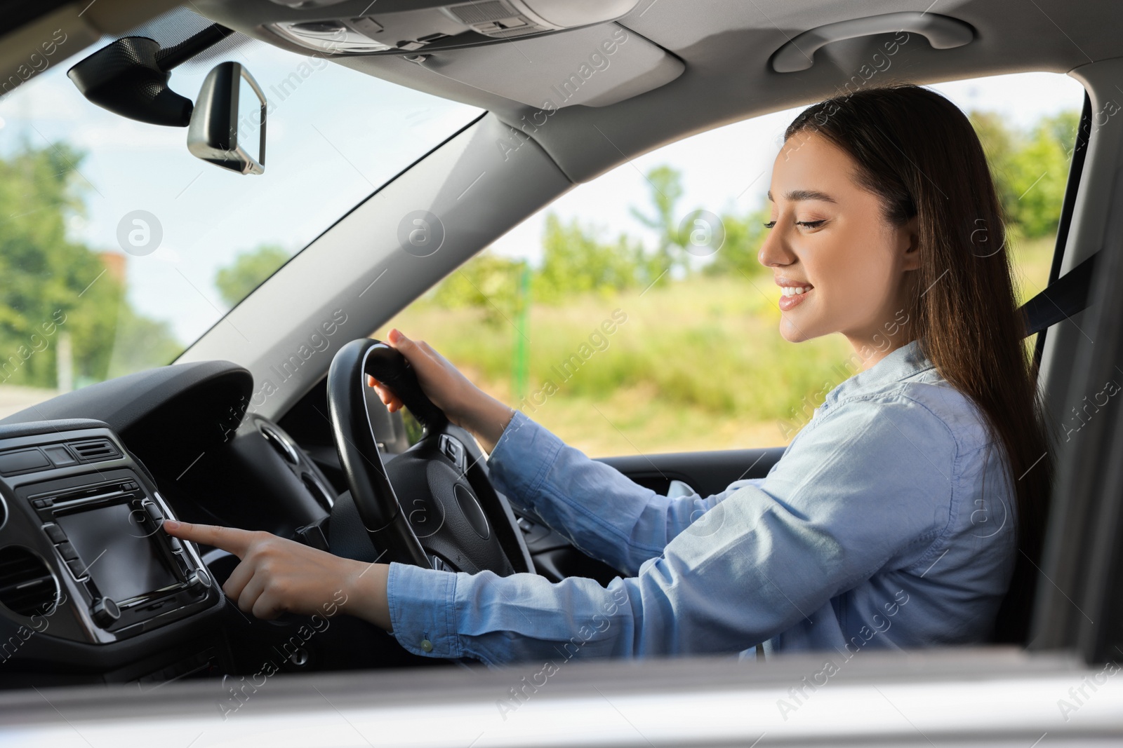 Photo of Choosing favorite radio. Beautiful young woman pressing button on vehicle audio in car