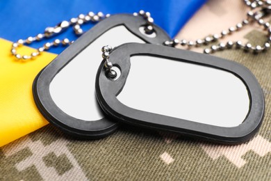 Photo of Military ID tags and Ukrainian flag on pixel camouflage, closeup