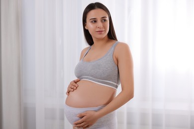Photo of Beautiful pregnant woman in comfortable maternity underwear indoors