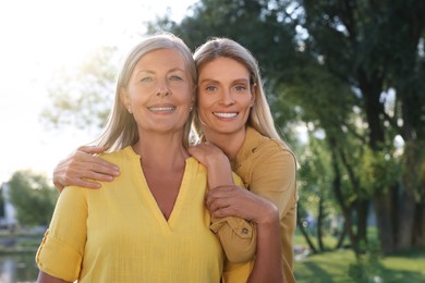 Photo of Family portrait of happy mother and daughter spending time together outdoors on sunny day