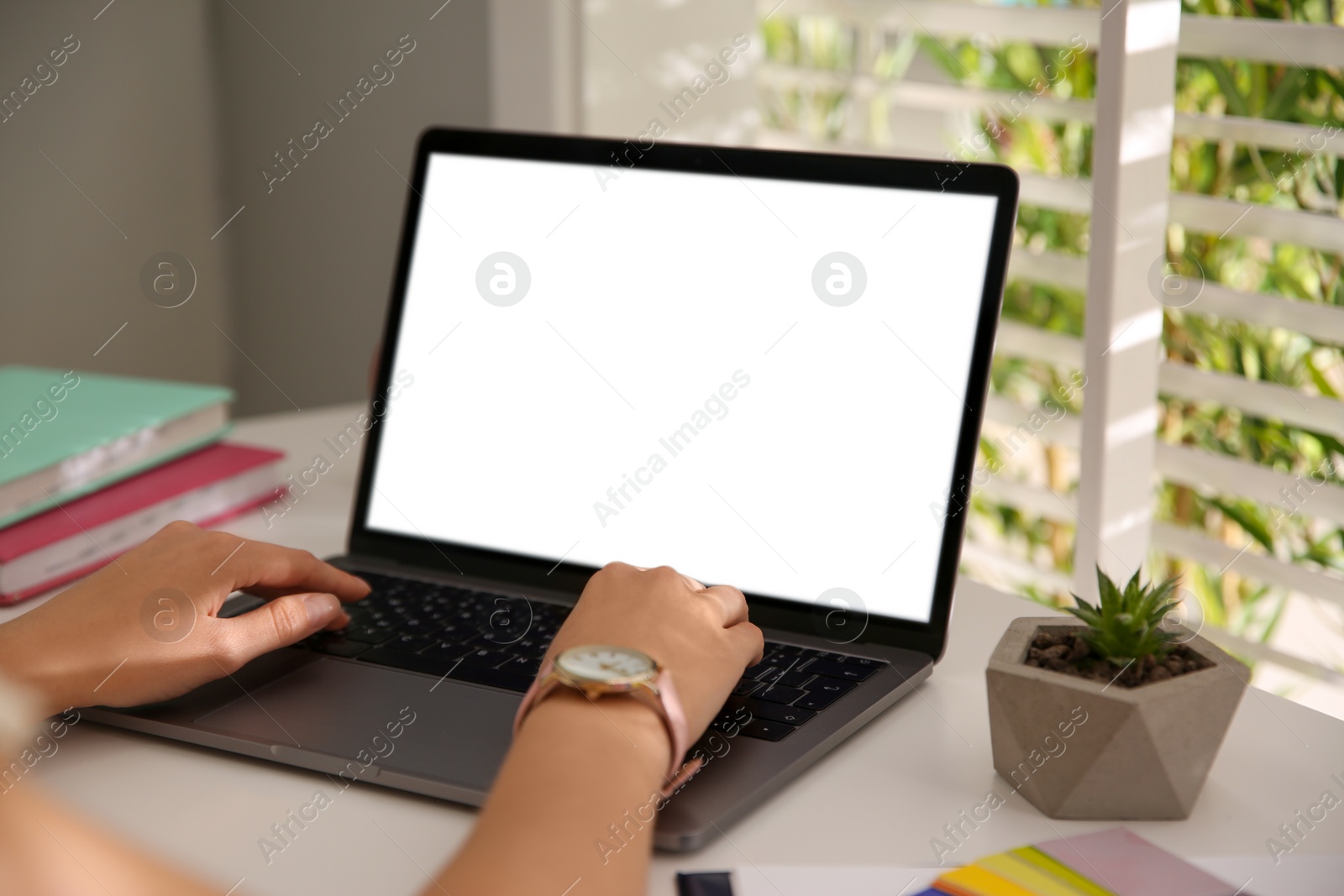 Photo of Woman working with modern laptop at white table, closeup. Space for design