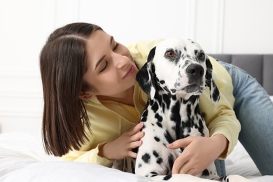 Beautiful woman with her adorable Dalmatian dog on bed at home. Lovely pet