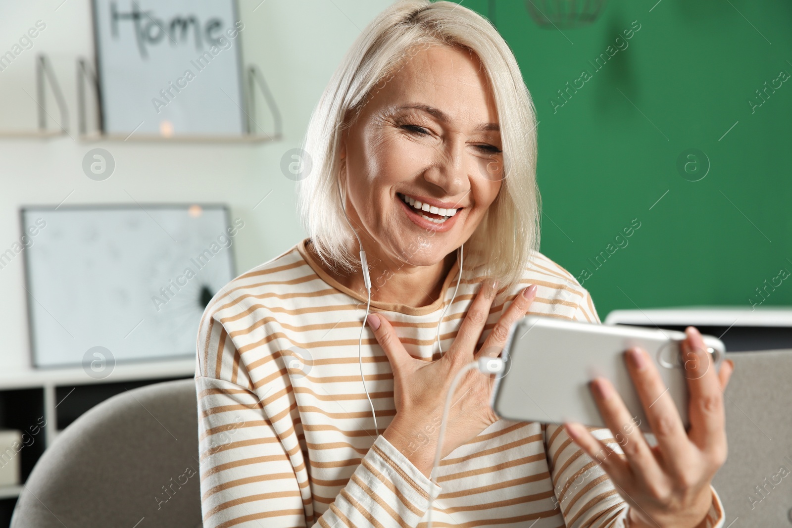 Photo of Mature woman using video chat on mobile phone at home