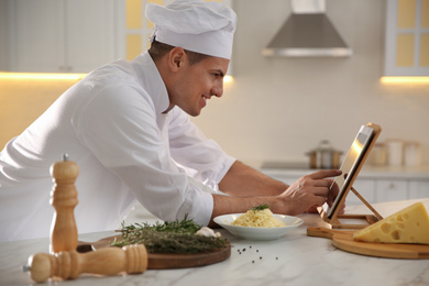 Photo of Chef with tablet cooking at table in kitchen