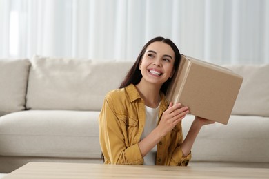 Photo of Happy young woman with parcel at home. Internet shopping