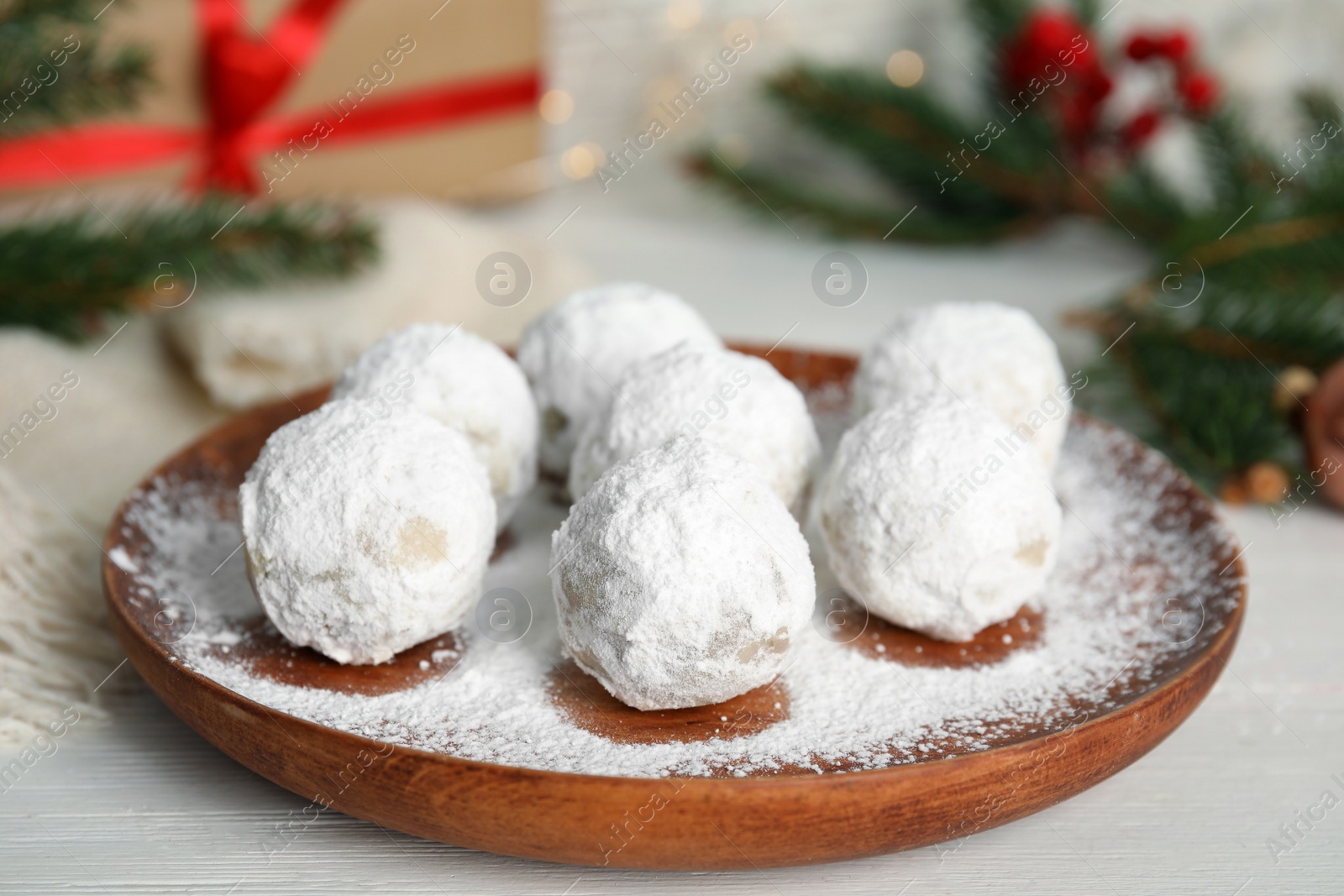 Photo of Wooden plate with tasty Christmas snowball cookies on table, closeup
