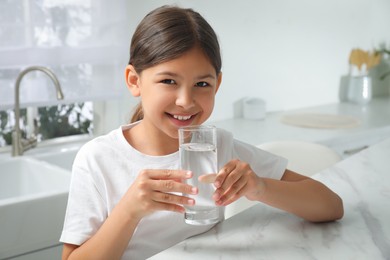 Photo of Girl drinking tap water from glass in kitchen