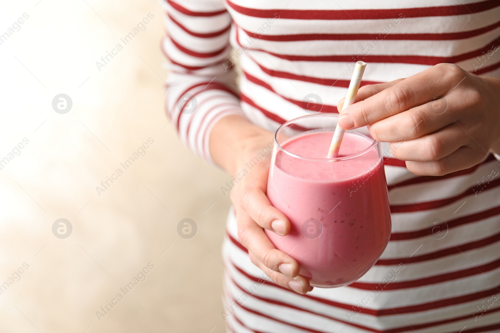 Image of Woman with glass of tasty smoothie on beige background, closeup