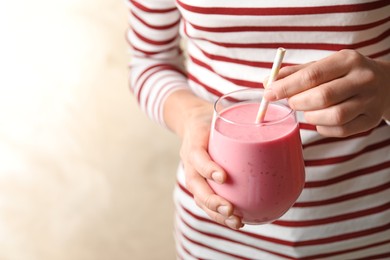 Image of Woman with glass of tasty smoothie on beige background, closeup