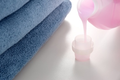 Photo of Pouring detergent into cap on white table. Laundry day