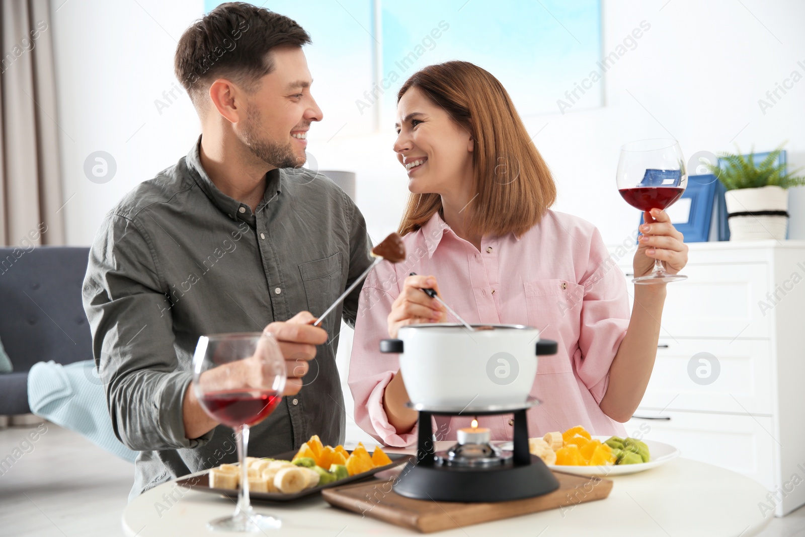 Photo of Happy couple enjoying fondue dinner at home