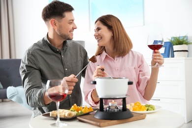 Photo of Happy couple enjoying fondue dinner at home