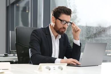 Photo of Man working on laptop at white desk in office