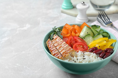 Photo of Tasty rice with beans and chicken meat on light grey marble table. Space for text